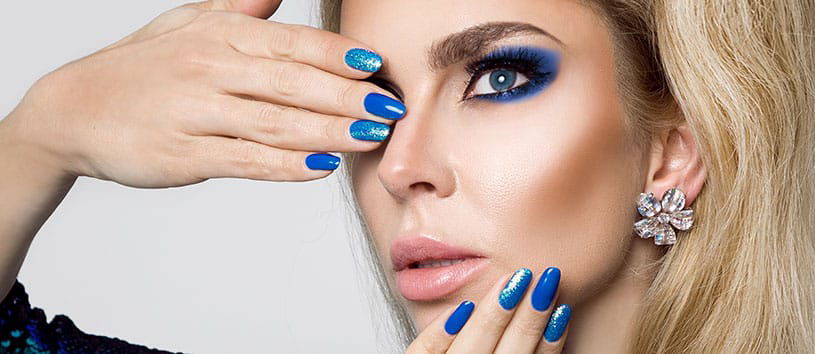 Woman with blue fingernails and blue eyeshadow.