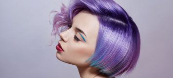 Side profile of a woman with short, purple/blue hair.