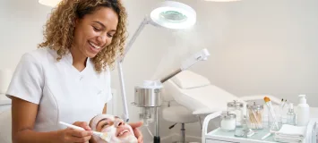 Spa Therapy student performing a facial treatment on a client in a professional spa training environment using skincare products and esthetics equipment.